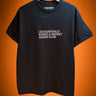 Black t-shirt with text saying I accidentally joined a secret anime club on a hanger against an orange background