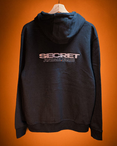 Black hoodie with 'Secret Anime Club' text on the back against an orange background